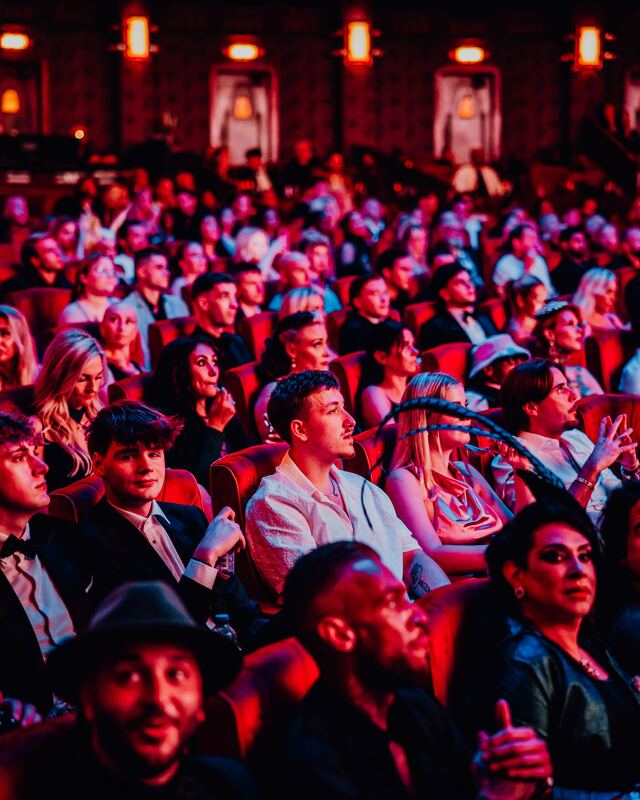 The audience of the F2F Creator Awards 2026 in red theatre seats, lit in red and blue, looking at the stage