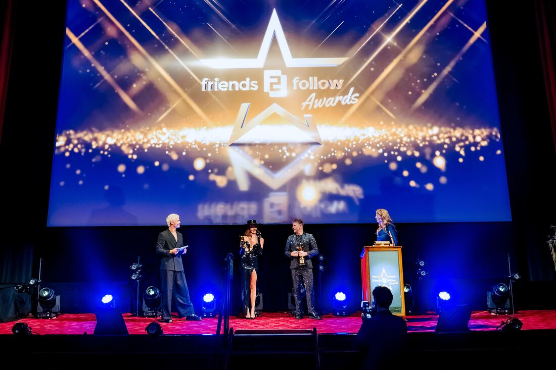 The stage of the F2F Creator Awards 2026 with the awards logo on the big screen, presenters at the lectern and blue stage light