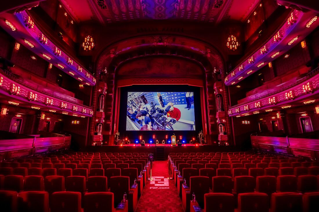 The empty auditorium of Theater Tuschinski before doors open: rows of red seats, the aisle and a film on the big screen